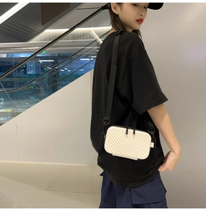 Detailed view of a white textured hardshell crossbody bag with an adjustable black strap