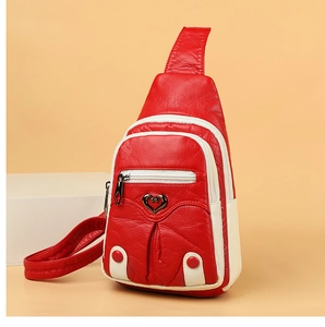 Detail of red pebbled PU leather chest bag with heart ornament and zipper compartments