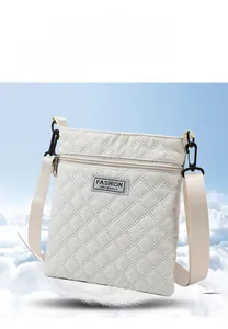 Détail d'un sac bandoulière blanc matelassé avec une large sangle et une étiquette mode