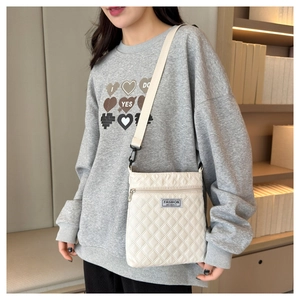 Détail du sac bandoulière matelassé beige avec logo FASHION INSTINCT et sangle large