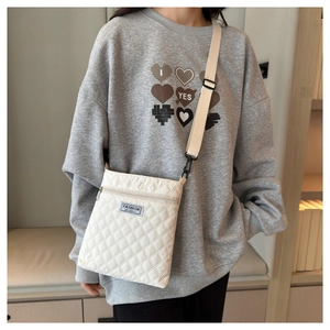 Détail du sac bandoulière blanc matelassé avec étiquette tissée fashion et sangle réglable