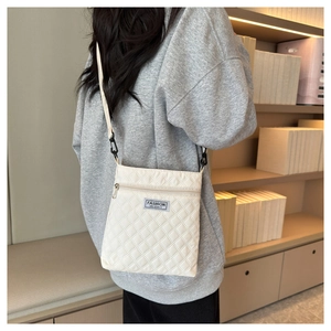 Gros plan du sac bandoulière matelassé blanc avec étiquette bleue et fermeture éclair