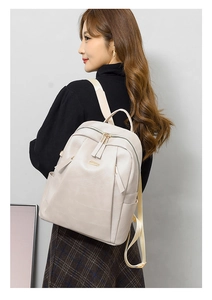 Beige faux leather backpack shown on model featuring adjustable straps and side pockets