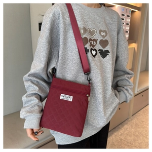 Détail de la sacoche matelassée bordeaux en nylon avec étiquette Fashion Instinct