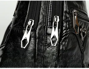 Close-up of double gun-metal zippers with geometric pulls and heart charm on soft PU leather