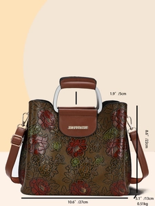 Detailed view of floral embossed pattern on vintage brown leather handbag with branding