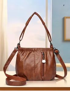 Close-up of vintage brown PU leather bucket bag with vertical zipper and canvas strap