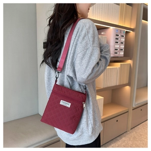 Détail du sac bandoulière matelassé rouge avec sangle réglable et étiquette de mode