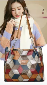 Detail of color-block tote bag with crocodile texture and metal chain strap accent