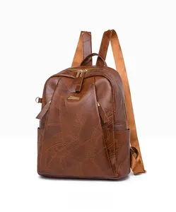 Detailed close-up of dark brown PU leather backpack with geometric stitching and gold zippers