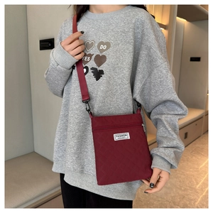 Détail du sac bandoulière matelassé bordeaux avec étiquette mode et poche zippée argent