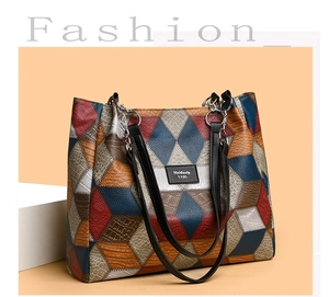 Detail of color-block tote bag featuring geometric leather patterns and metallic chain straps