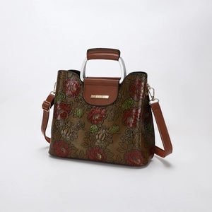 Macro detail of red peony embossed leather handbag with golden hardware and handles