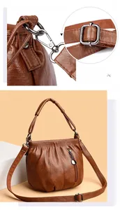 Detail of silver hardware hooks and adjustable shoulder strap on brown PU leather bucket bag