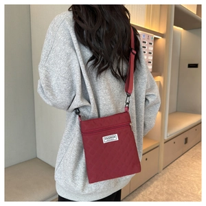 Sac bandoulière matelassé rouge en nylon avec étiquette logo sur un mannequin