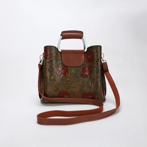 Detailed view of vintage peony relief on a brown handbag with detachable strap