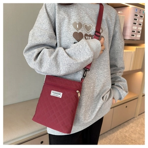 Gros plan d'un sac bandoulière matelassé rouge vin avec écusson Fashion Instinct