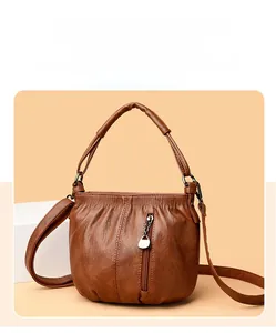 Detail of a brown vintage PU leather crossbody bag with soft pleated texture and metal zipper