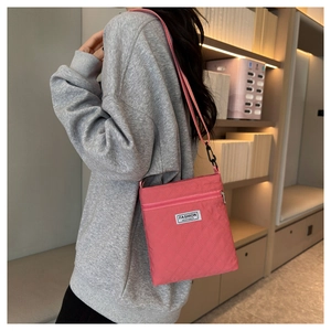 Détail d'un sac bandoulière en nylon rose matelassé avec écusson logo blanc