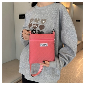 Détail du sac bandoulière matelassé rose montrant l'étiquette et la texture en nylon