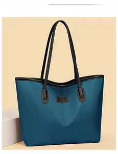 Dettaglio macro della borsa tote in nylon blu navy con patch logo in pelle nera