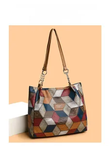Detail of color-block tote bag featuring geometric leather panels and metal chain strap