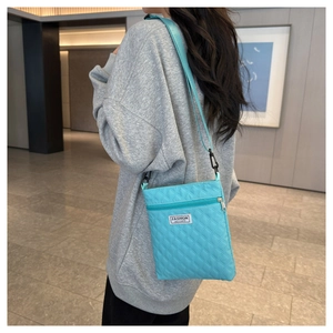 Détail du sac bandoulière matelassé bleu clair avec motif losange et étiquette