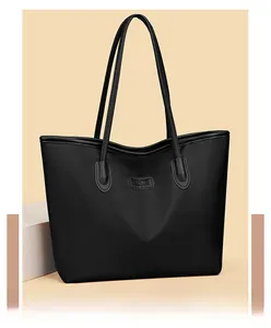 Dettaglio ravvicinato di una grande borsa tote nera in Oxford con logo minimalista in pelle