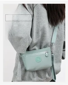 Rückansicht eines Models mit einer minzgrünen Nylon-Umhängetasche mit verstellbarem Gurt