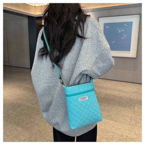 Détail du sac à bandoulière matelassé bleu clair avec texture losange et étiquette