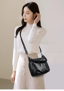 Detail of black soft PU leather bucket bag with vintage pleated texture and slim strap