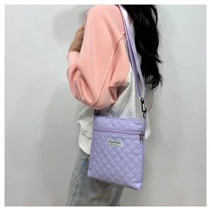 Détail du sac bandoulière matelassé lilas avec poche zippée et étiquette de marque