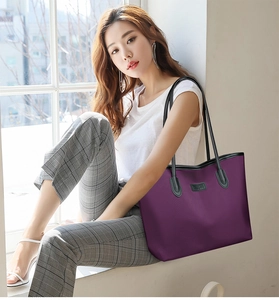 Dettaglio della borsa tote in tessuto oxford viola con manici neri in pelle su un modello