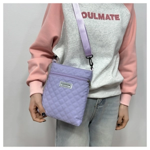 Détail d'un sac bandoulière matelassé lavande avec étiquette tissée et sangle réglable