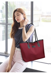 Dettaglio della borsa tote bordeaux in tessuto Oxford con logo e manici in pelle
