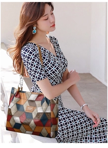 Detail of color-block geometric tote bag with brown leather handles and metal chain links