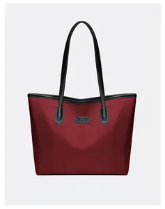 Dettaglio macro della borsa tote in tessuto oxford rosso con manici neri e logo