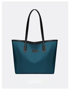 Dettaglio della borsa tote in nylon blu navy con manici in pelle nera e patch logo