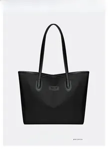 Dettaglio frontale della borsa tote nera con logo in pelle e trama in tessuto resistente