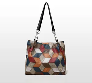 Detail view of geometric patchwork tote bag with crocodile pattern and chain strap