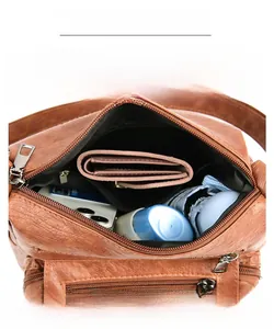 Macro view of a brown pebbled leather crossbody bag showing spacious interior compartments