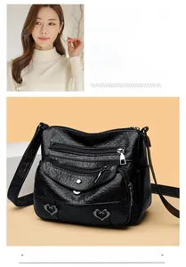 Detail of black multi-pocket crossbody bag with heart charms and soft PU texture