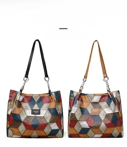 Detail view of large tote bags with geometric patchwork and metallic chain handles