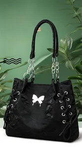 Detail of black tote bag featuring embossed texture, silver butterfly logo and chain strap