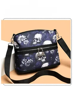 Detail of skull and floral print on dark blue shoulder bag with wide woven strap