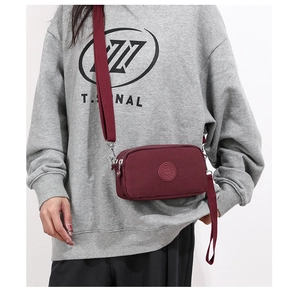 Detailansicht der burgunderroten Nylontasche mit Reißverschlussfächern und Logo