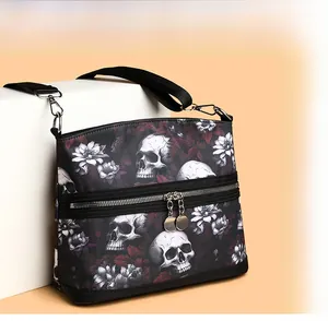 Detail of skull floral print crossbody bag with dual metal zippers and wide strap
