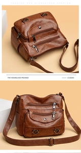Detail of vintage brown leather crossbody bag with heart buckles and multi-zipper pockets