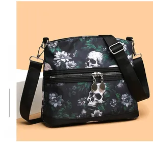 Detail of skull floral print shoulder bag with dual zipper pockets and adjustable strap