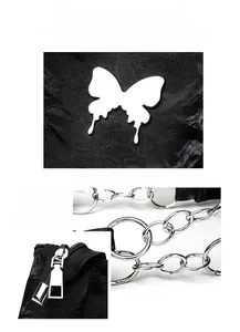 Detail of silver butterfly hardware and polished metal chain on a black crossbody tote bag